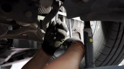 Auto Mechanic Adjusts Car Wheel Alignment in Service Garage Technician Uses Tools on Vehicle