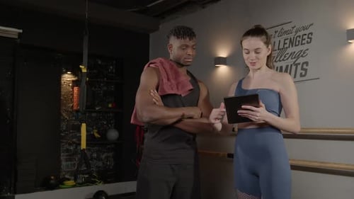 Trainer Explains Workout Plan to Client at Gym