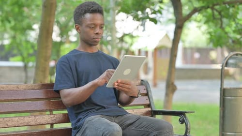 Young Adult Using Tablet on Park Bench