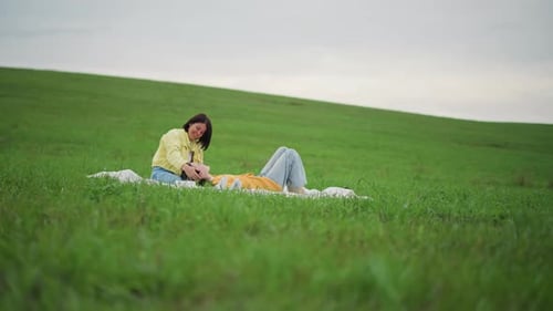 Women Relaxing on Blanket in Green Grassy Field