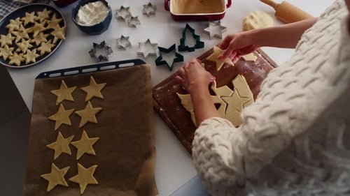 High angle view of unrecognizable woman cutting out gingerbread cookies from the dough. Shot with RE