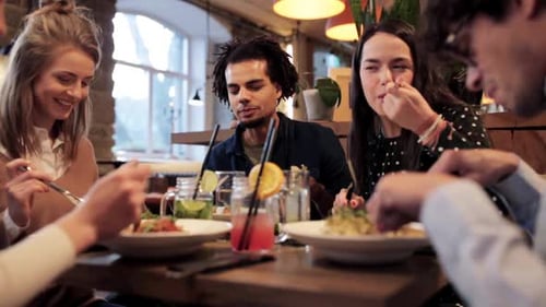 Happy friends enjoying food drinks and festive holidays at a restaurant