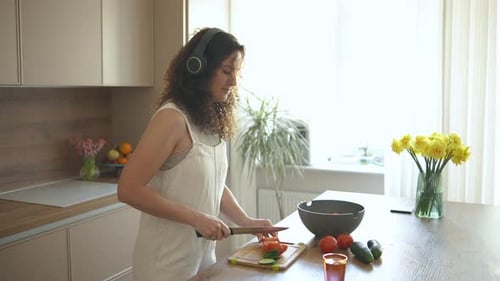 Woman Preparing a Salad in Kitchen with Headphones