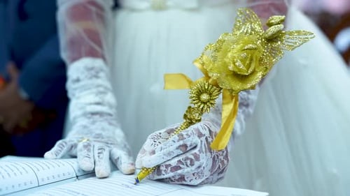 Eine Braut unterschreibt den Ehevertrag mit einem elegant verzierten Stift in Gold.