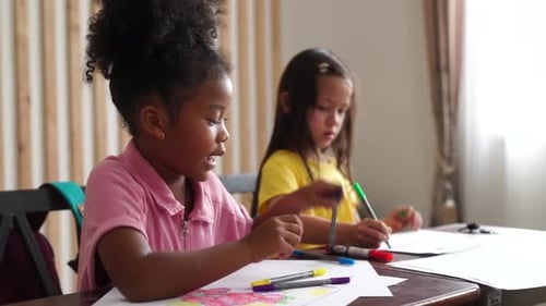 School children writing in books with pencils in classroom