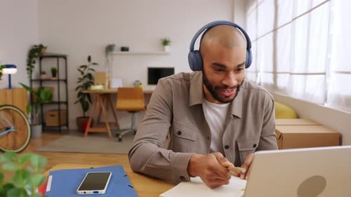 Man in Headphones Works at Desk with Laptop