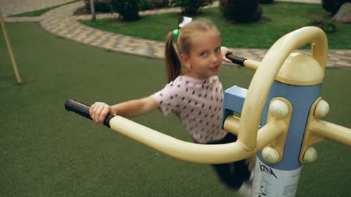 Child Exercising on Outdoor Fitness Equipment at Park Playground in Sunny Afternoon