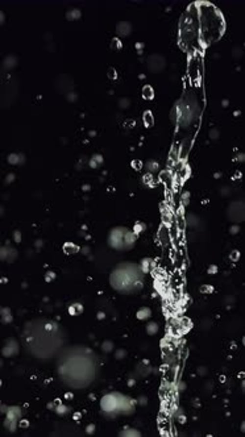 Delicate Water Splashing And Falling Against A Dark Backdrop