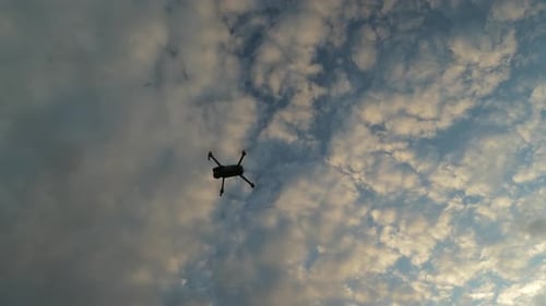 Drohne schwebt, dreht sich und fliegt dann seitwärts nach rechts unter Himmel und Wolken