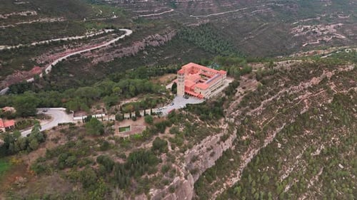 Panoramaaufnahme aus der Luft, die gekonnt ein Kloster inmitten der Umarmung eines üppigen grünen Berges einfängt