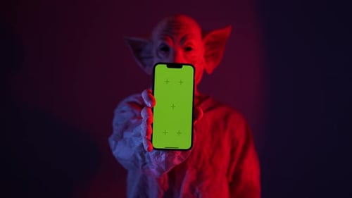 Man with Horror Pig Mask Holding Green Screen Smartphone in Front Him