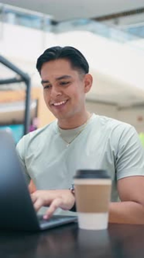 Happy Young Man Typing On His Laptop In A Mexican Shopping Mall