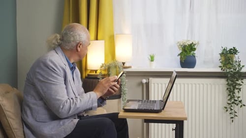 Man Using Smartphone and Laptop Inside