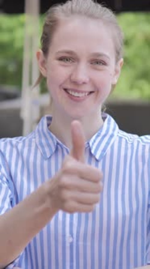 Thumbs Up by Young Woman Sitting in Cafe Terrace, Vertical Video