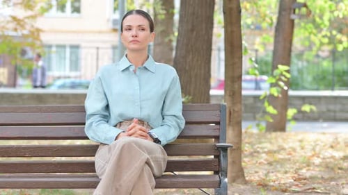 Woman Awaits on Park Bench Checking Smart Watch