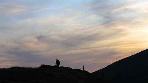 Dark Silhouettes of Hikers Trekking on Evening Mountain Terrain