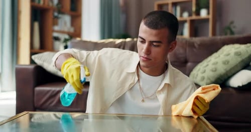 Young Adult Man Cleaning Glass Table in Home