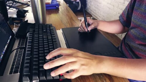 Man graphic designer working using his laptop, keyboard and tablet