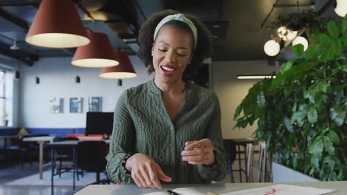 Portrait of happy african american businesswoman talking and looking at camera at office