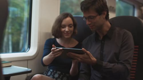 Couple on Train Sharing a Digital Tablet