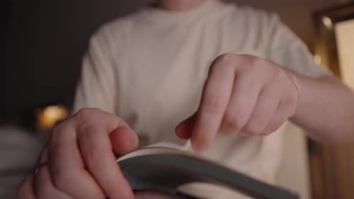 Frustrated Man Tearing a Blank Notebook Page in Dim Room Symbolizing Creative Block Lack of