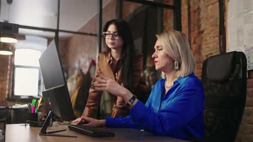 Two Businesswomen Discussing Project Or Agreement In Office Looking At Computer Display Teamwork