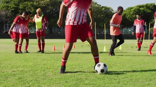 Video of diverse group of male football players warming up and kicking ball