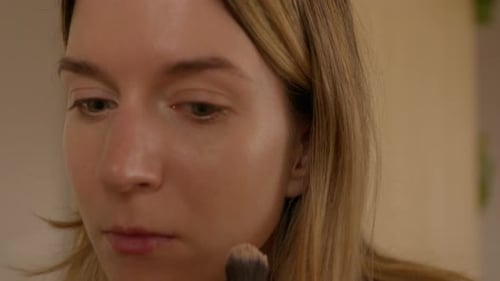 Woman Applies Makeup to Face with Brush