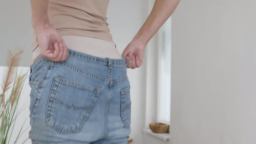 Close Up Back View Portrait of Unrecognizable Young Woman Putting on Denim Pants and Turning to