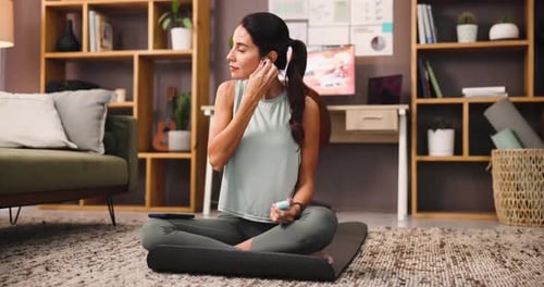 Woman Puts Earbuds In, Uses Smartphone On Mat