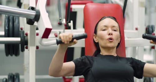 Woman Exercises on Assisted Chest Press Machine in Gym
