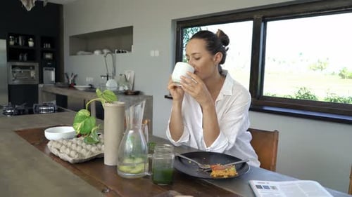 Woman Enjoying Coffee and Breakfast in Modern Kitchen