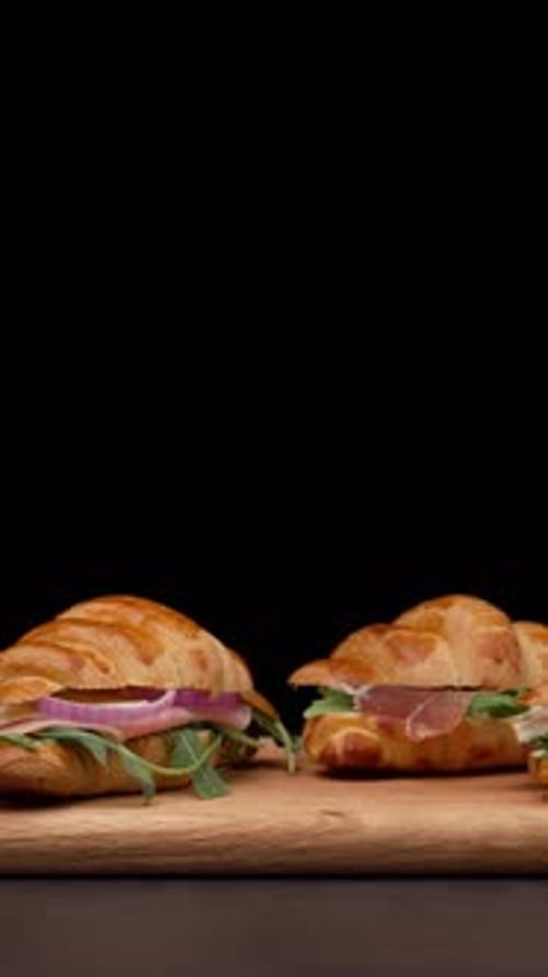 Vertical Video, Croissant Sandwiches On A Wooden Table, Black Background, Front View