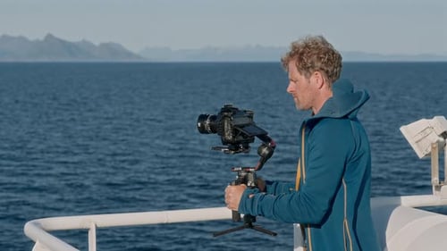 Cineasta em jaqueta com capuz filma Ferry Journey