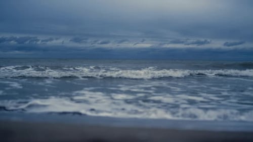 Ocean storm waves crashing splashing on beach sand background at dusk evening view