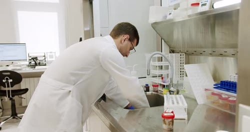 Scientist Rinsing Equipment in Bright Laboratory Sink