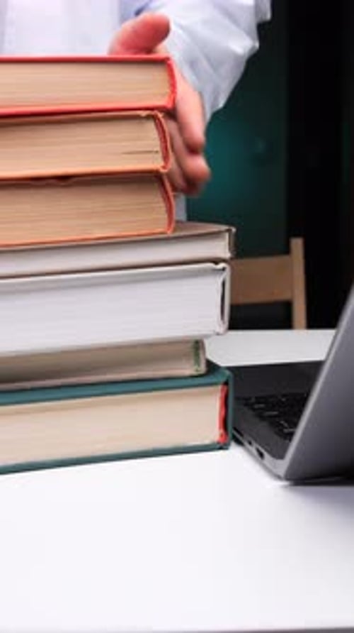 Stack of books on desk with laptop