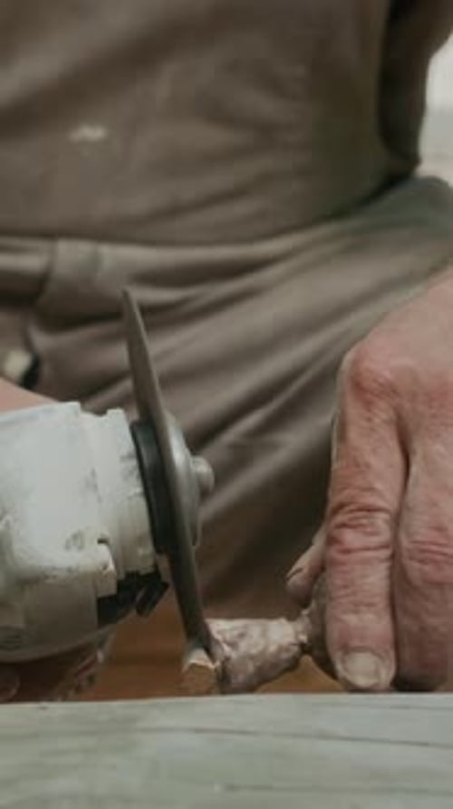 Vertical of Male Sculptor Carving Stone Piece with Angle Grinder