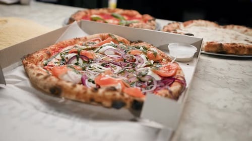 Delicious beautiful pizza with fish in a pizza box in a restaurant, ready for delivery