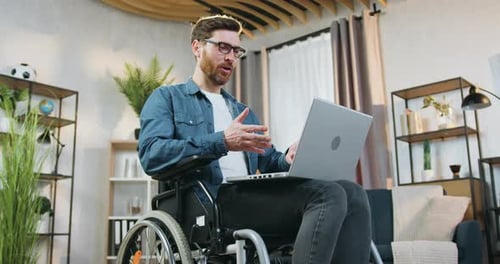 Man in Wheelchair Using Laptop in Home Office