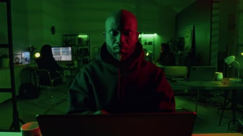 Male Computer Criminal Pulling Hood over Head while Breaking Server Security