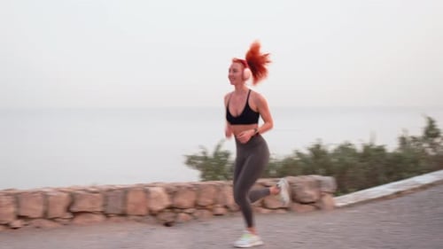 Woman Runs Along the Coastline in the Morning