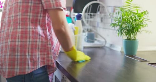 Person Cleaning Kitchen Counter With Spray and Cloth