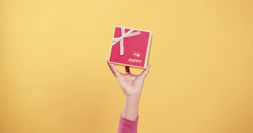 Close up women's hand holds a red gift box in her palm raise with shaking and lowers it down the scr