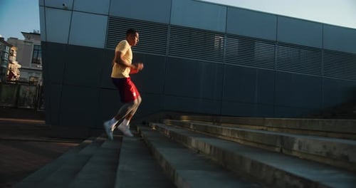 Athletic Man Running Up Concrete Steps in City