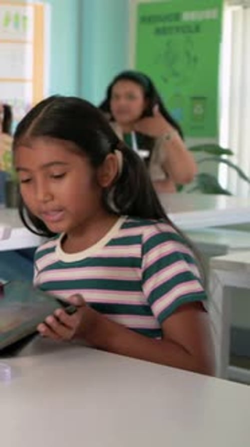 Vertical video: Tapping tablet girl in tee adjusting 2 turbines at desk matching blades to tablet