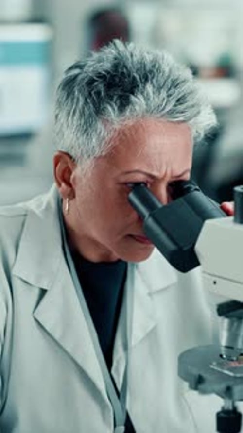 Woman Researcher Looking Through Microscope in Laboratory