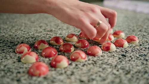 Hand Arranging Round Red and White Candies