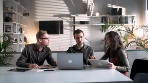 Colleagues And Clients Talking Strategy With Laptop And Tablet In Creative Office Productive