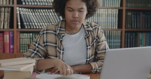 Diligent Female Student Concentrated on Self Education Using Laptop Typing and Writing in Notebook